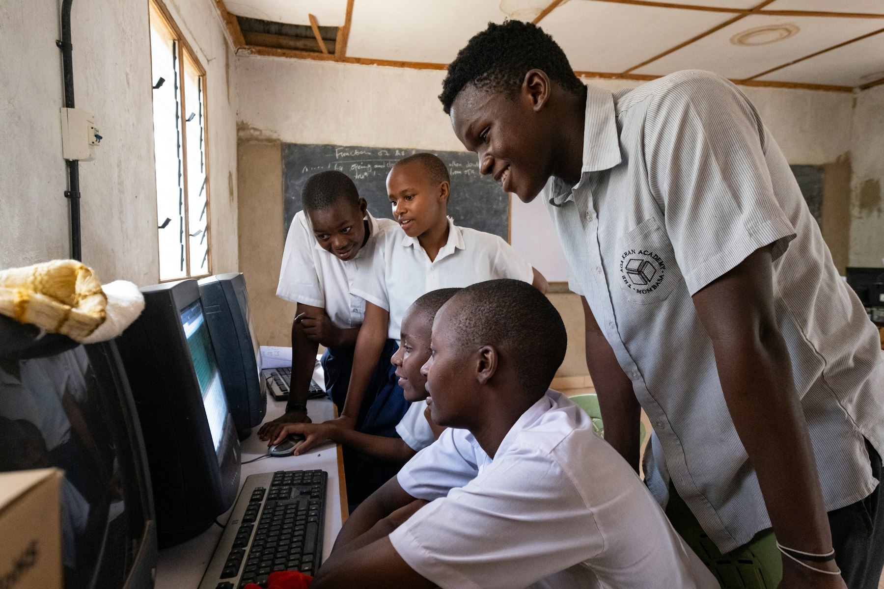 Aga Khan Academy Mombasa student Raphael Mwachiti (right) assisted in the computer lab at his former primary school, Saint Joseph’s, encouraging the young students to study harder so they could “make something of themselves”.